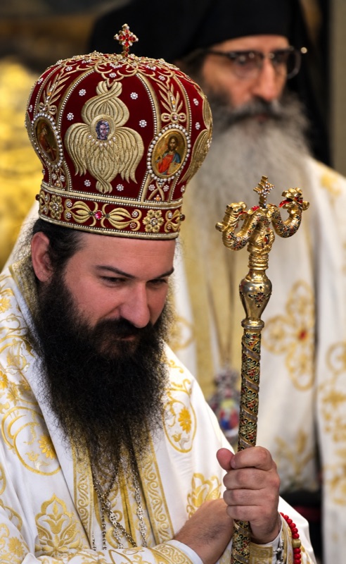 The bishop in a jewelled mitre holding his crozier, with a clergyman standing behind him