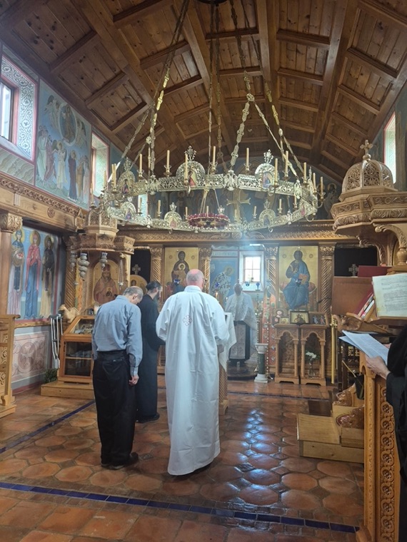 The interior of the wooden church: a brass chandelier hanging beneath a vaulted ceiling before the iconostasis