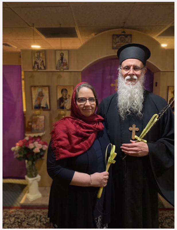 Fr. Jacob and a parishioner holding woven palm crosses in the church