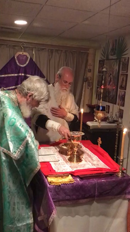 Two priests at a candlelit table during an evening service